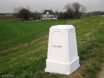 Loenen heeft geen plaatsnaambord, maar een 'plaatsnaamsteen'. Het is een 19e-eeuwse, rijksmonumentale grenspaal. Op de achtergrond de 19e-eeuwse opvolger van het Huis te Loenen.