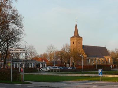 Het dorp Mastenbroek is zodanig dun en verspreid bebouwd dat het geen 'bebouwde kom' heeft. Vandaar witte plaatsnaamborden i.p.v. blauwe. Op de achtergrond de van oorsprong middeleeuwse kerk met toren uit 1845. (© H.W. Fluks)