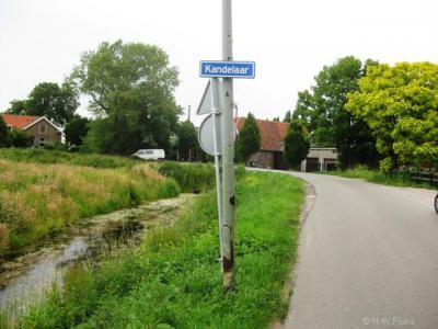 De buurtschap Kandelaar is van een wel erg 'zuinig' plaatsnaambordje voorzien. Het heeft namelijk de uitvoering van een straatnaambordje, maar dat is het toch niet, want de weg ter plekke heet namelijk Kandelaarweg.